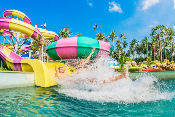 Happy family splashing into a giant wave pool at Siam Water Park in Bangkok, Thailand.