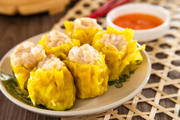 Kanom Jeeb, Thai steamed dumplings filled with minced pork and shrimp, often served with a savory soy sauce for dipping.